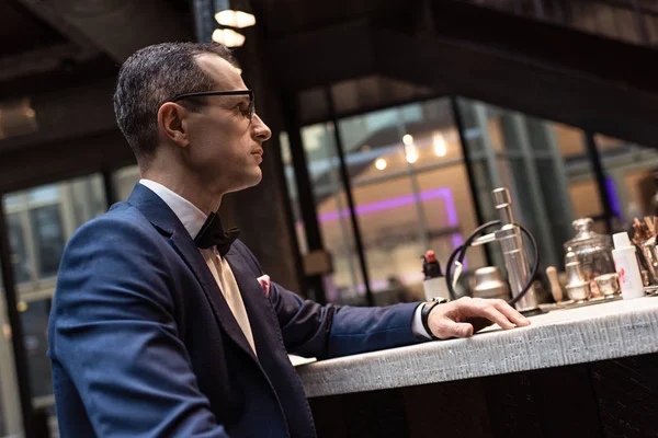 Bel homme en costume élégant assis au comptoir du bar du restaurant de luxe — Photo de stock