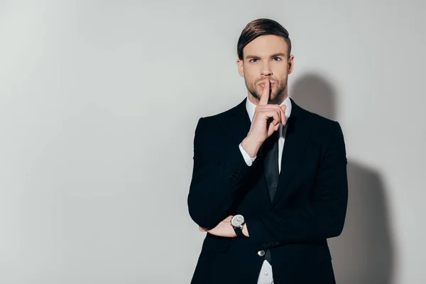 Junger selbstbewusster Geschäftsmann im Anzug zeigt Schweigegegeste auf weißem Hintergrund — Stockfoto