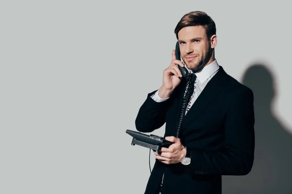 Молодий впевнений бізнесмен у костюмі говорить по телефону на білому тлі — стокове фото