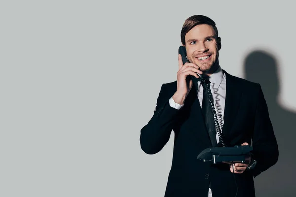 Jovem empresário sorridente de terno falando ao telefone no fundo branco — Stock Photo