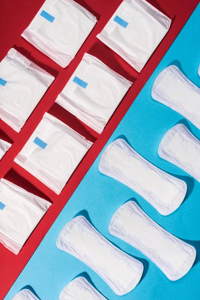 Top view of rows of pads and daily liners on red and blue — Stock Photo