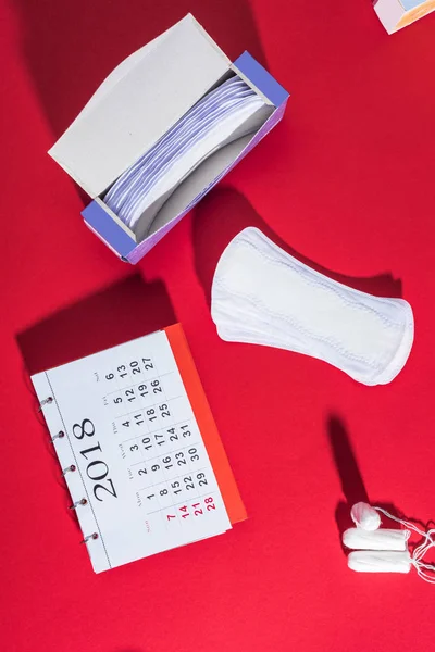 Vista superior de tampões, forros diários e calendário em vermelho — Fotografia de Stock