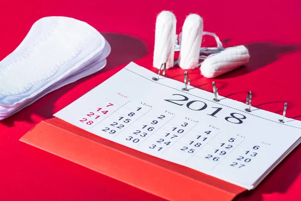 Tampons, tampons quotidiens et calendrier sur rouge — Photo de stock