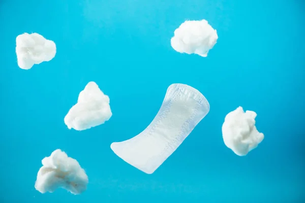 Falling daily pad and pieces of cotton isolated on blue — Stock Photo