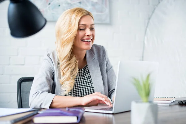 Усміхнена бізнес-леді використовує ноутбук на роботі — стокове фото
