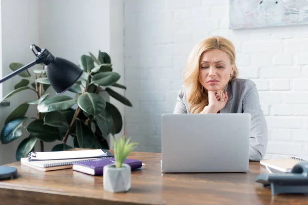 Sad businesswoman looking at laptop in office — Stock Photo