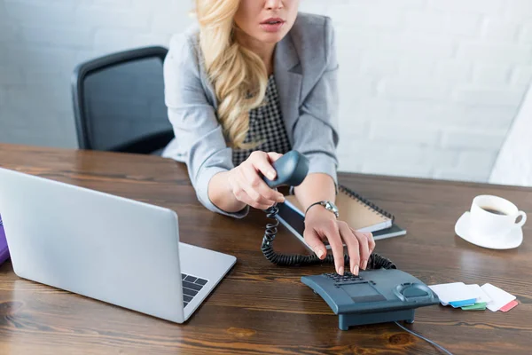 Cropped image of businesswoman dialing number on stationary telephone — Stock Photo