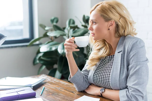 Seitenansicht einer Geschäftsfrau, die bei der Arbeit Kaffee trinkt — Stockfoto