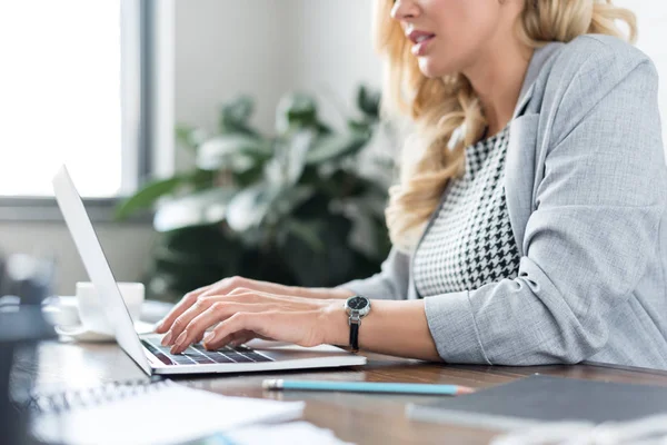 Image recadrée de femme d'affaires en utilisant un ordinateur portable au travail — Photo de stock