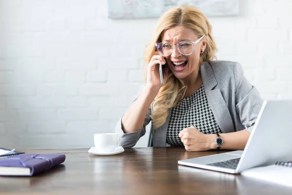 Shocked screaming businesswoman talking by smartphone in office — Stock Photo