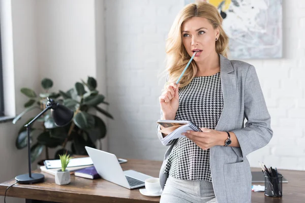 Mujer de negocios mordiendo lápiz y mirando hacia otro lado - foto de stock