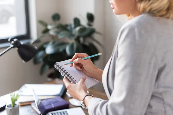 Cropped image of businesswoman writing something in notebook at office — Stock Photo