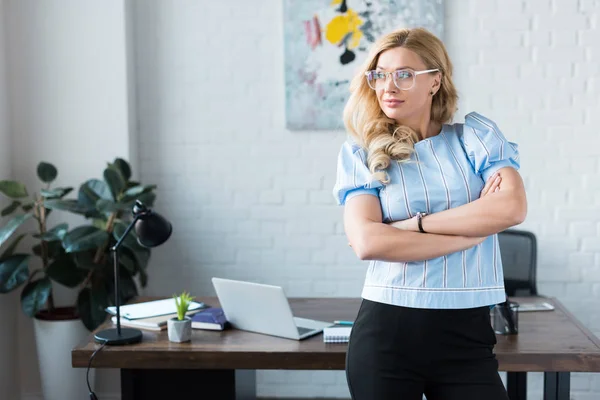 Businesswoman standing with crossed arms and looking away — Stock Photo