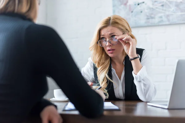 Businesswoman holding glasses and looking away — Stock Photo