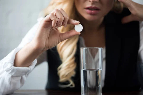 Image recadrée de femme d'affaires avec pilule et verre d'eau — Photo de stock