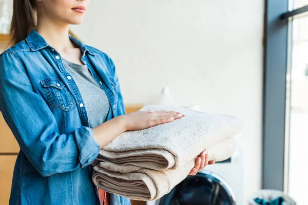 Tiro recortado de mujer joven sosteniendo toallas limpias en casa - foto de stock