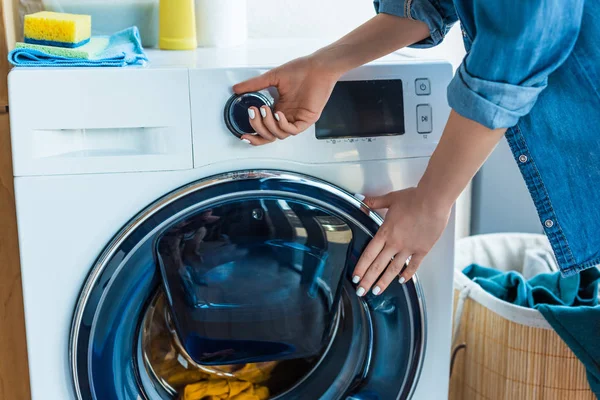 Tiro recortado de la mujer usando lavadora en casa - foto de stock