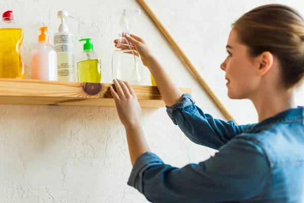 Junge Frau schaut auf Regal mit verschiedenen Reinigungsgeräten — Stockfoto