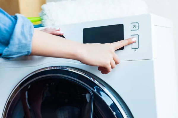 Close-up visão parcial da mulher usando máquina de lavar roupa em casa — Fotografia de Stock