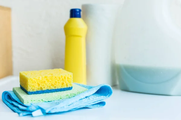 Vista de cerca de toallas, esponjas y recipientes de plástico con líquidos de limpieza - foto de stock