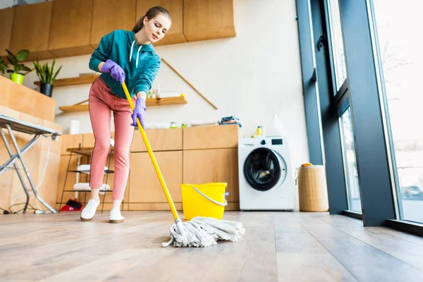 Vue à angle bas de la jeune femme nettoyant la maison avec une serpillière — Photo de stock