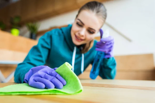 Hermosa mujer joven sonriente limpieza de casa con trapo y líquido de limpieza - foto de stock