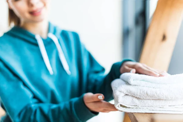 Cropped shot of young woman holding clean white towels at home — Stock Photo
