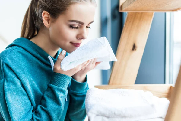 Sonriente joven mujer sosteniendo limpio blanco toalla en casa - foto de stock