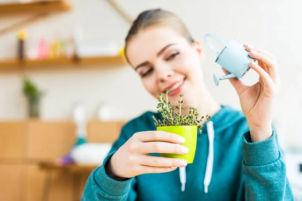 Heureux jeune femme arrosage pot plante à la maison — Photo de stock