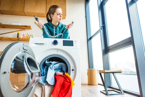 Jovem mulher inclinada na máquina de lavar roupa quebrada — Fotografia de Stock