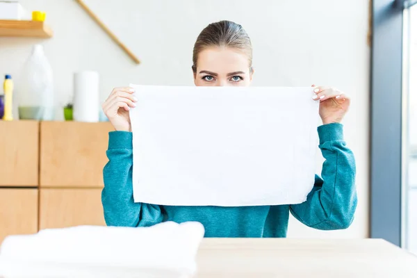 Junge Frau hält sauberes weißes Handtuch in der Hand und blickt in die Kamera — Stockfoto