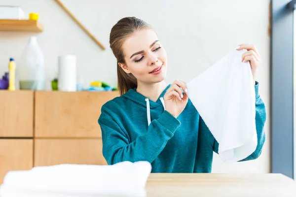 Sonriente joven mujer sosteniendo toalla blanca sobre la mesa - foto de stock