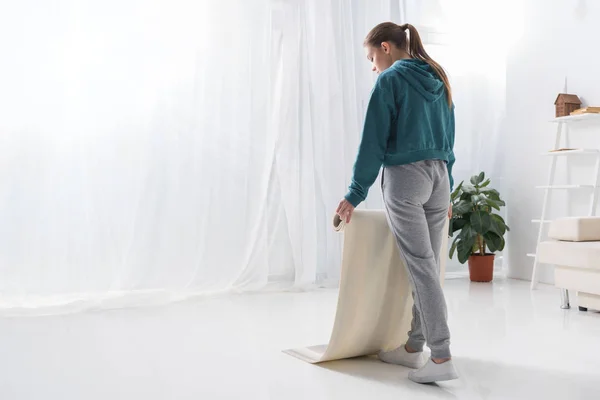 Jovem mulher colocando tapete de ioga no chão em casa — Fotografia de Stock
