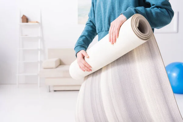 Cropped image of girl twisting yoga mat at home — Stock Photo