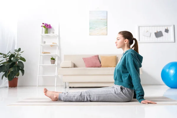 Вид збоку дівчини, що сидить на йога килимок вдома — стокове фото