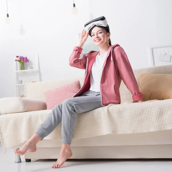 Sorridente ragazza in possesso di auricolare realtà virtuale e guardando lontano a casa — Foto stock