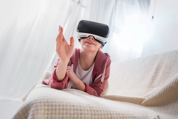 Улыбающаяся девушка трогает что-то с помощью гарнитуры виртуальной реальности дома — стоковое фото