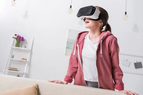 Menina surpresa assistindo algo com fone de ouvido realidade virtual em casa — Fotografia de Stock