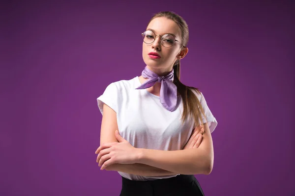 Stylish girl with crossed arms looking at camera isolated on purple — Stock Photo