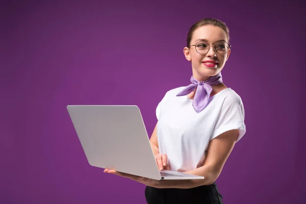 Lächeln Mädchen mit Laptop und wegschauen isoliert auf lila — Stockfoto