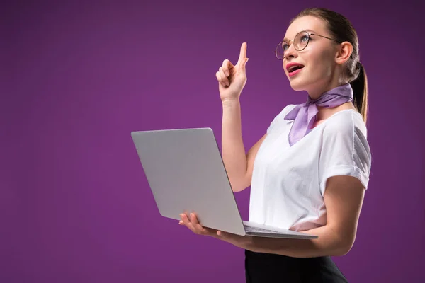 Menina segurando laptop e mostrando gesto ideia isolado em roxo — Fotografia de Stock