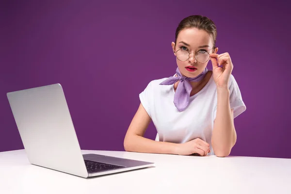 Girl touching glasses and looking at camera isolated on purple — Stock Photo