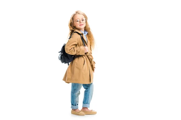 Side view of kid in glasses holding bag and wearing beige trench coat isolated on white — Stock Photo