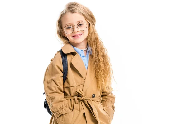 Criança em óculos vestindo casaco de trincheira e segurando saco no ombro isolado no branco — Fotografia de Stock