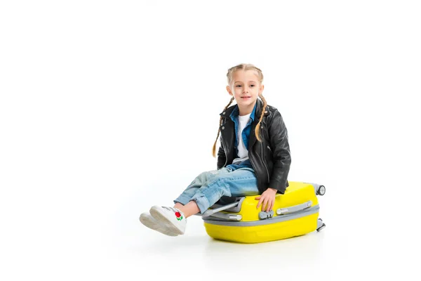 Little tourist with pigtails sitting on yellow wheel suitcase isolated on white — Stock Photo