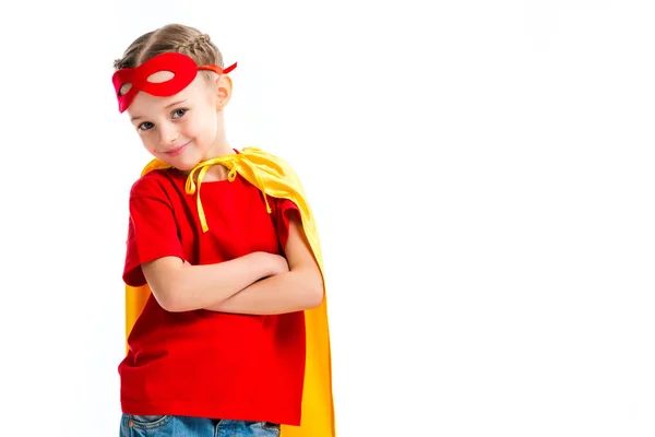 Pequeña superchica sonriente usando capa amarilla con máscara roja para los ojos en la frente aislada en blanco - foto de stock