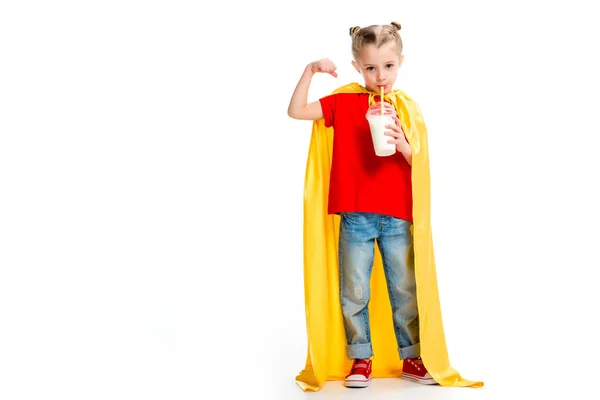 Supergirl em capa amarela bebendo milkshake e mostrando músculos na mão isolados em branco — Fotografia de Stock