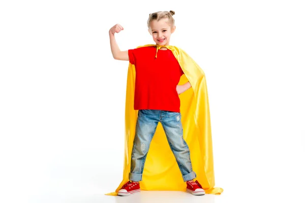 Smiling supergirl in yellow cape showing muscles on hand isolated on white — Stock Photo