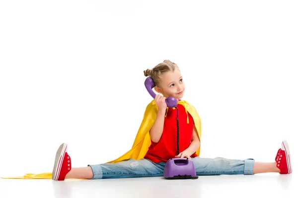 Happy supergirl sitting on split and talking on phone isolated on white — Stock Photo