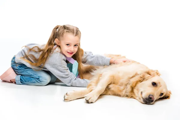 Retrato de niño feliz tocando perro beige acostado aislado en blanco - foto de stock